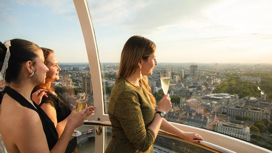 Women enjoying champagne on the London Eye with cityscape views.