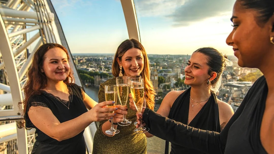 Group toasting with champagne inside London Eye capsule during sunset.