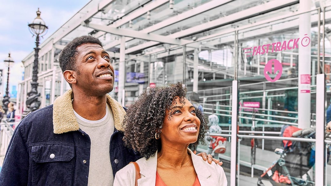 Couple smiling near Fast Track entrance to the London Eye.