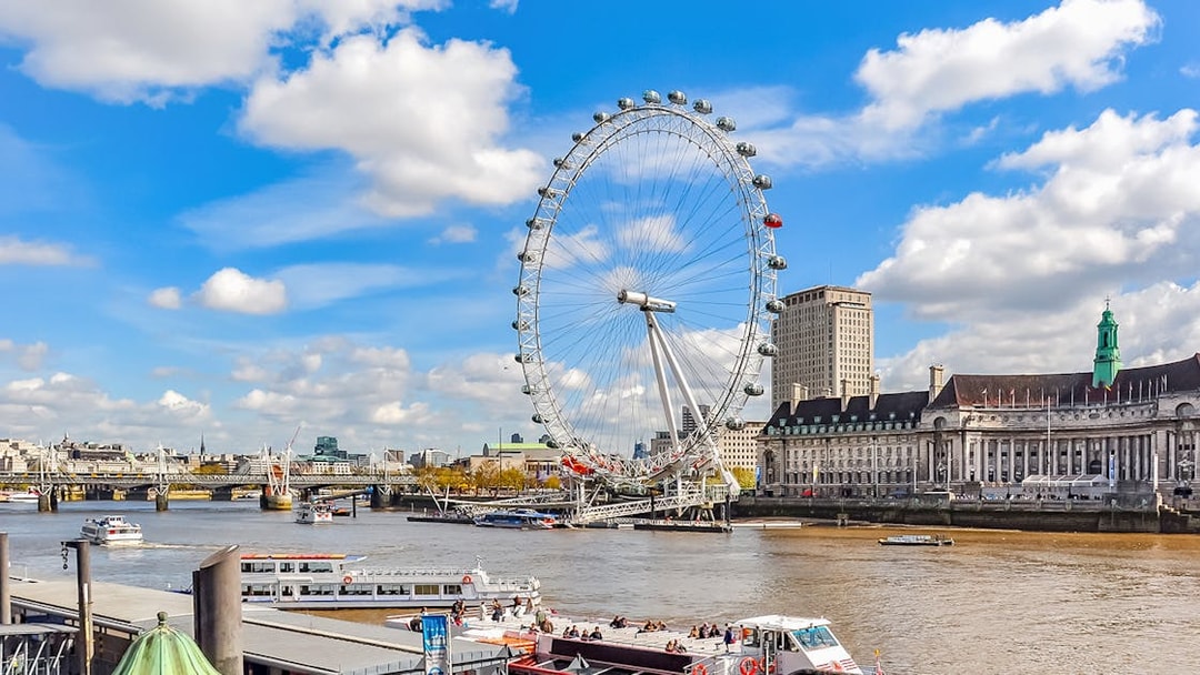 Tourists on a boat near the London Eye with city skyline in the background.