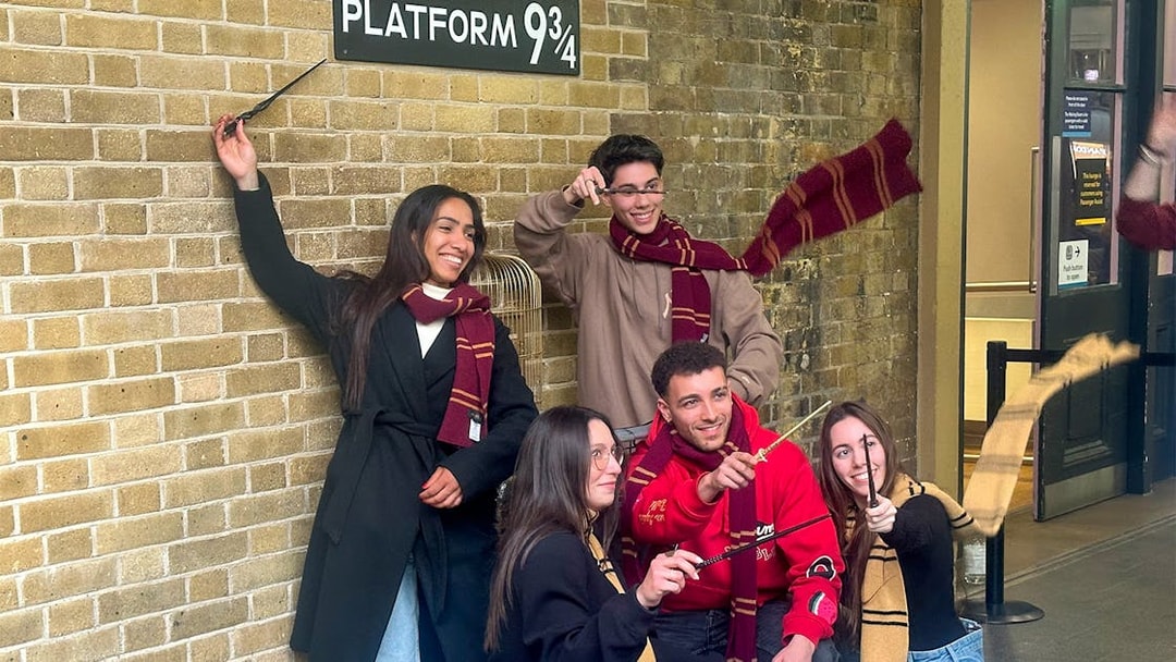 Visitors posing with wands at Kings Cross Platform 9 3/4 in London.