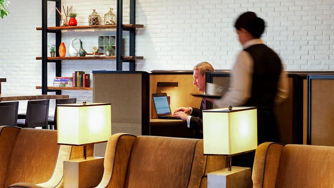 Heathrow Plaza Premium Lounge seating area with guest using laptop and staff serving.