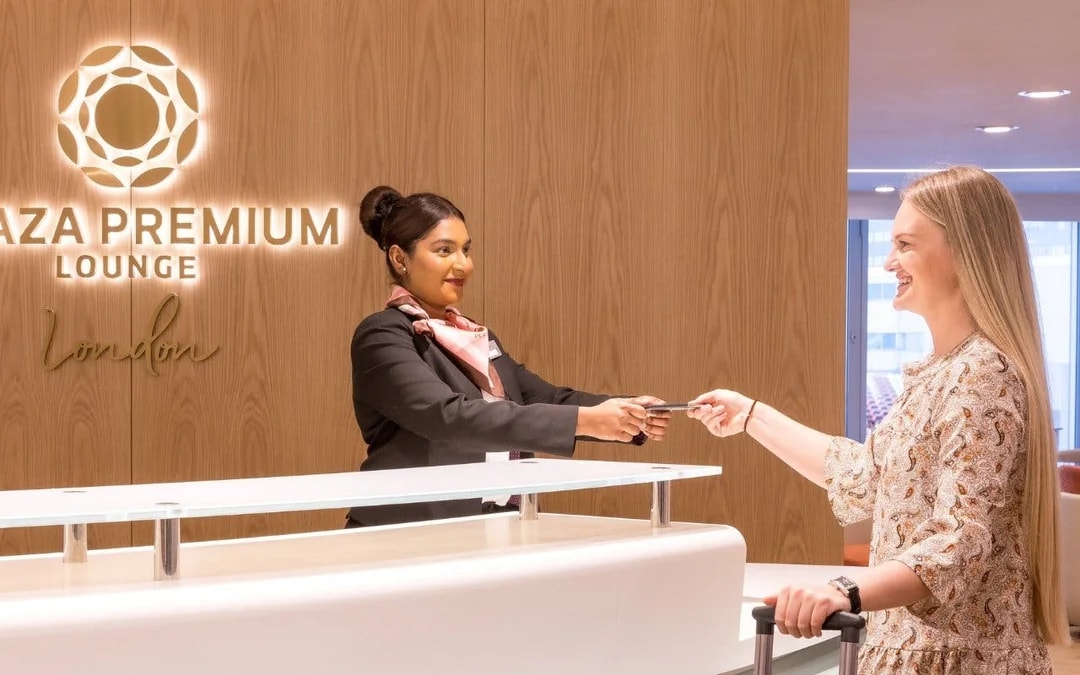 Plaza Premium Lounge staff assisting traveler at London Heathrow Terminal 4.