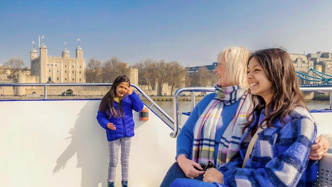 Family enjoying a London sightseeing cruise with Tower of London in the background.