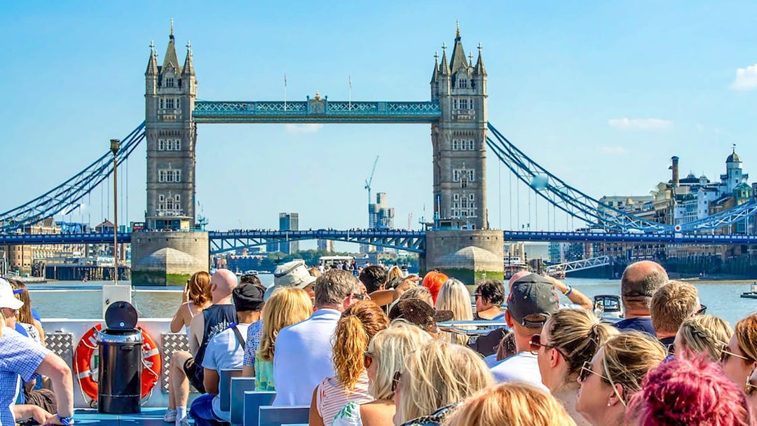 Sightseeing cruise passengers view Tower Bridge on the Thames in London.