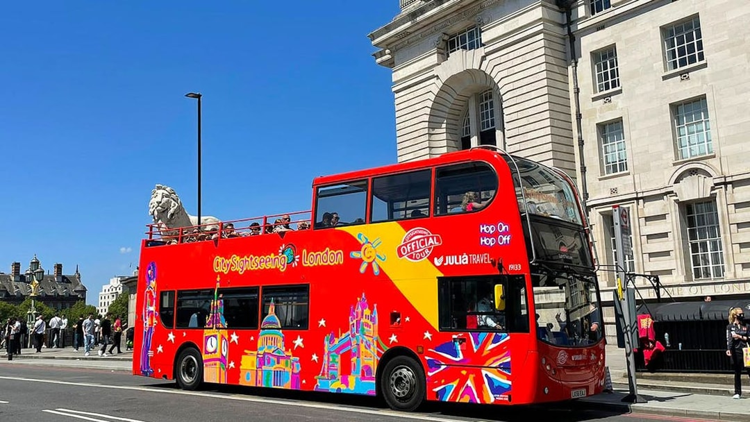 Open-top red double-decker bus on London street, part of Thames River Hop-On Hop-Off Cruise Tour.