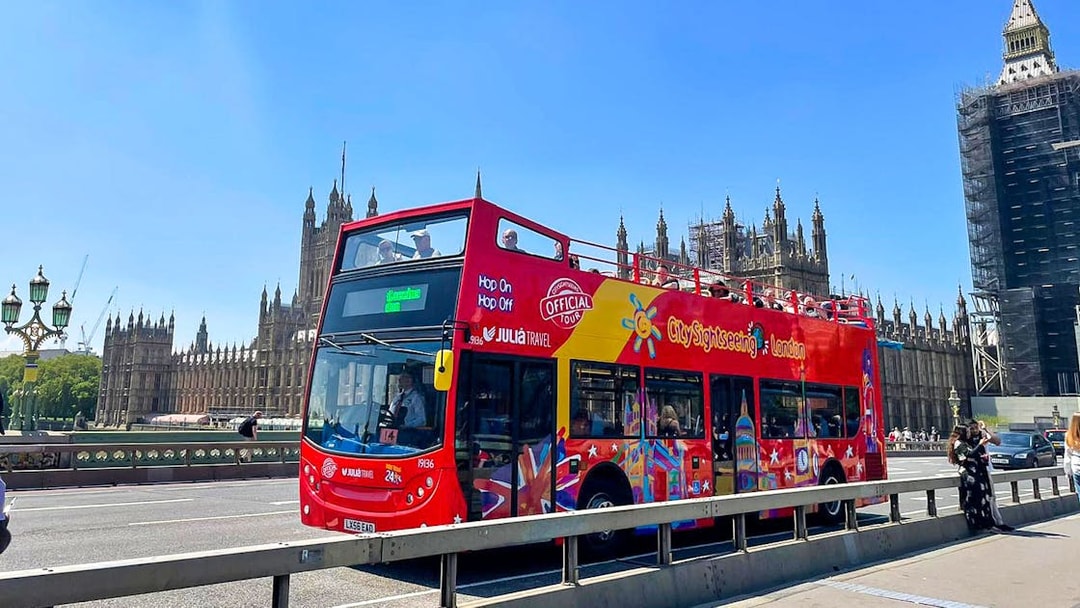 Open-top red tour bus on Westminster Bridge with Houses of Parliament in London.