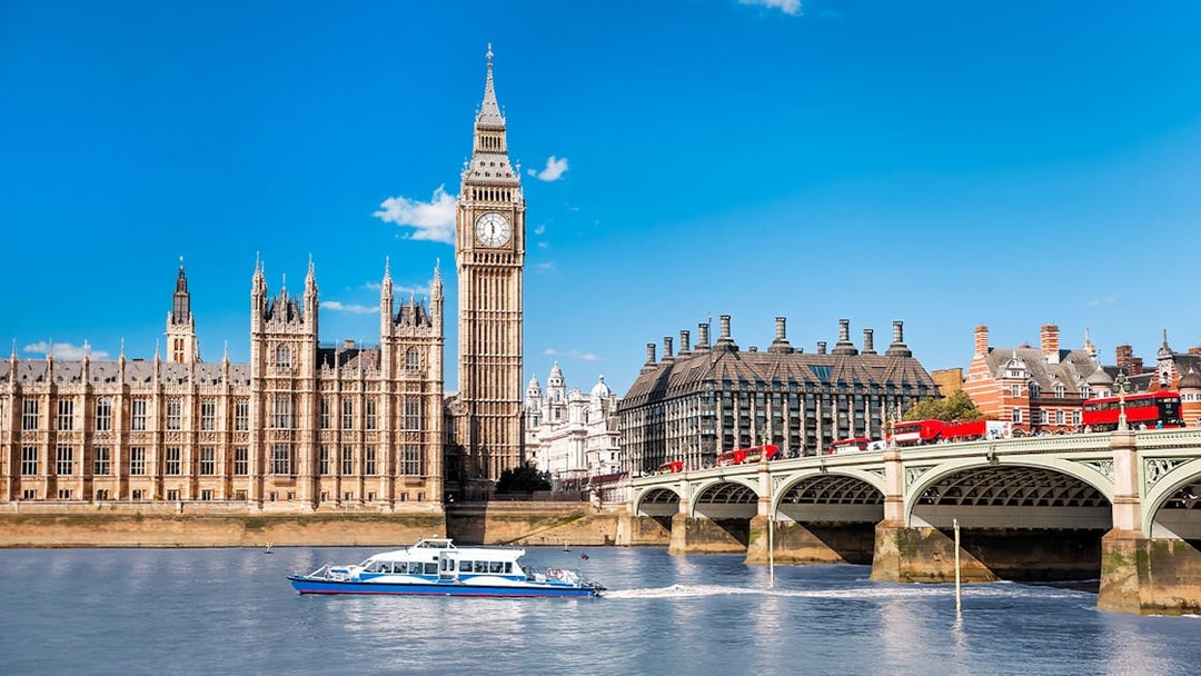 Thames River cruise boat near Big Ben and Westminster Bridge, London.