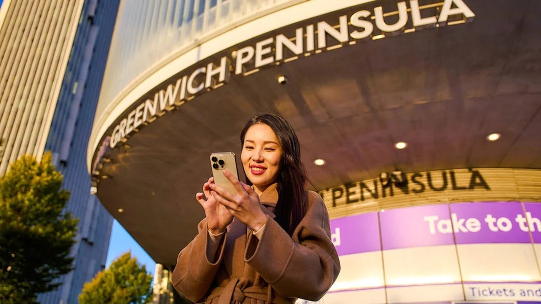 Guest using phone at Greenwich Peninsula, London near IFS Cloud Cable Car.