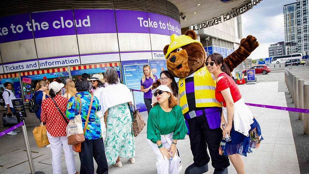 Guests posing with a mascot at IFS Cloud Cable Car entrance in London.
