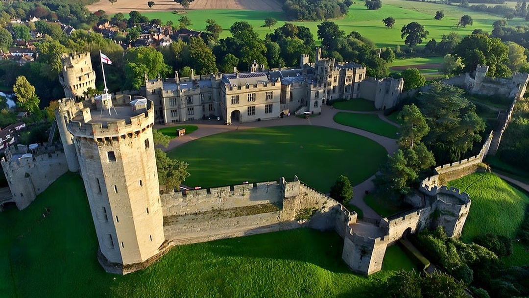 Aerial view of Warwick Castle surrounded by lush greenery, part of the Stratford, Oxford, Cotswolds tour.