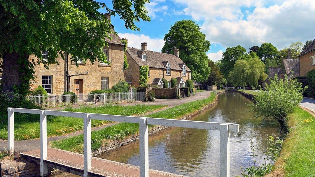 Cotswolds village scene with stone cottages and a canal, part of Stratford, Oxford, Cotswolds & Warwick Castle Tour.