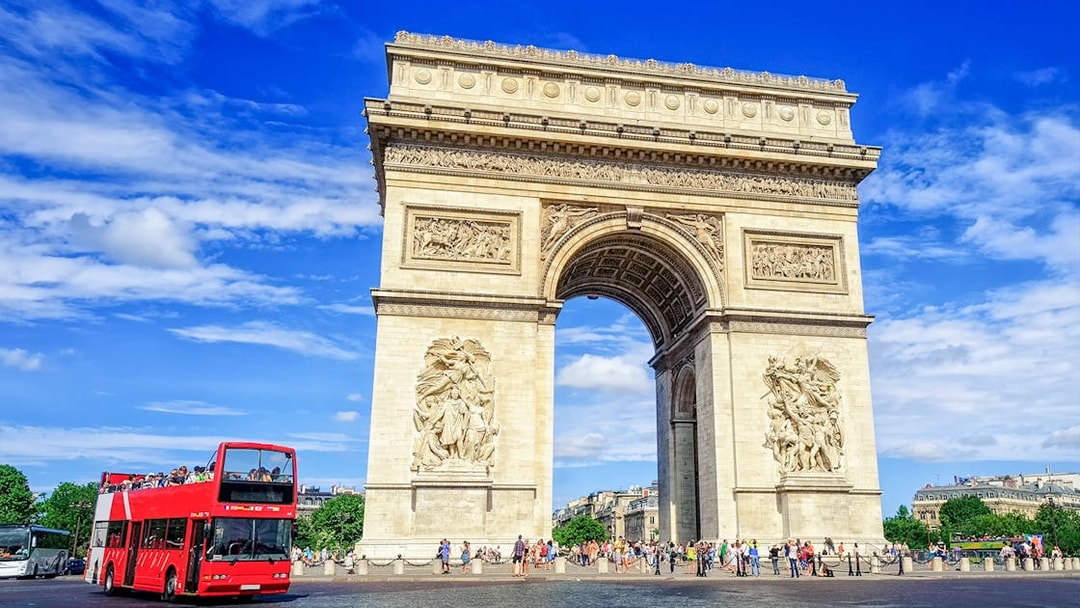 Arc de Triomphe with a red tour bus in Paris, part of the Paris in a Day Guided Tour.