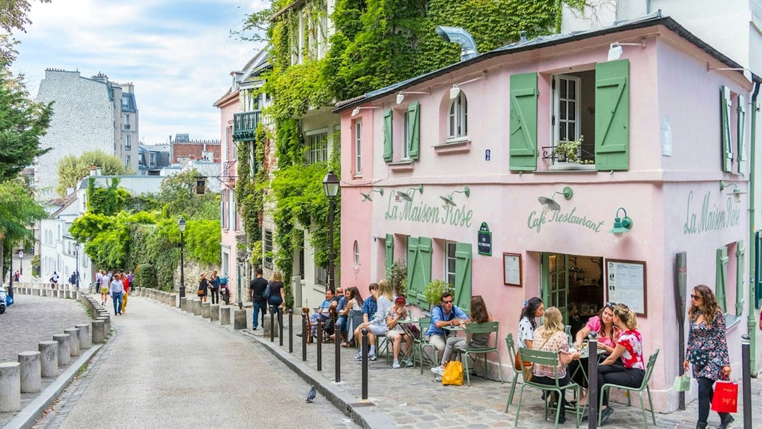 Café La Maison Rose on a cobblestone street in Montmartre, Paris, with people dining outside.