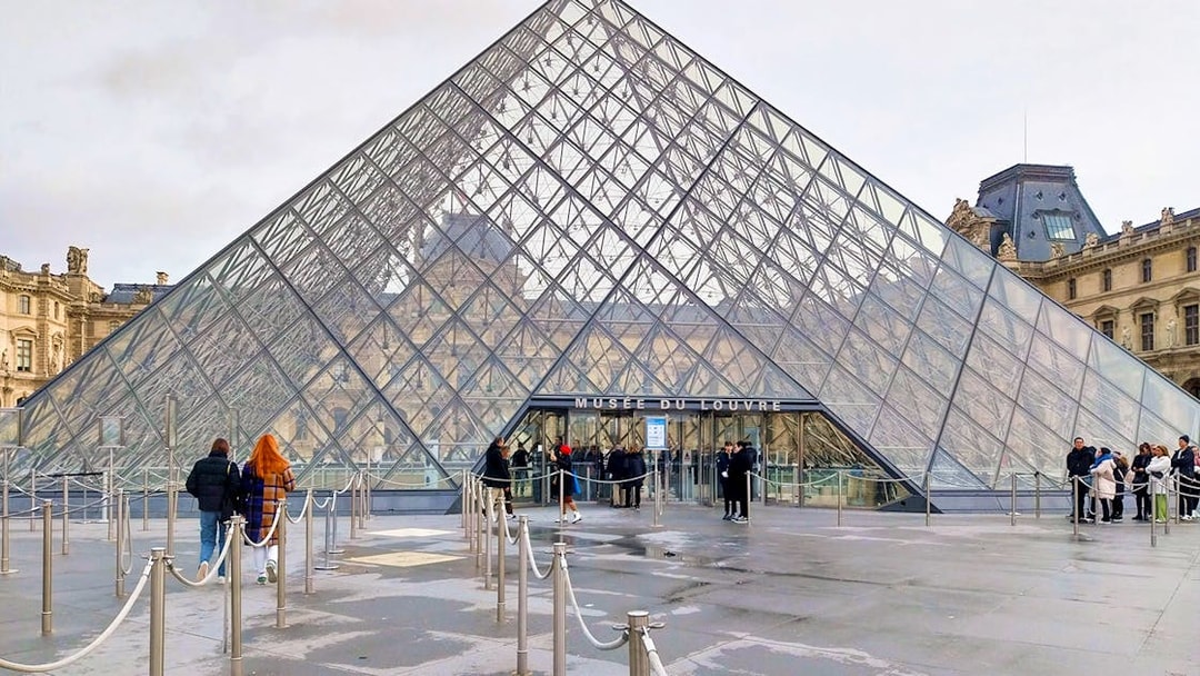 Tourists entering the Louvre Museum through the glass pyramid entrance in Paris.