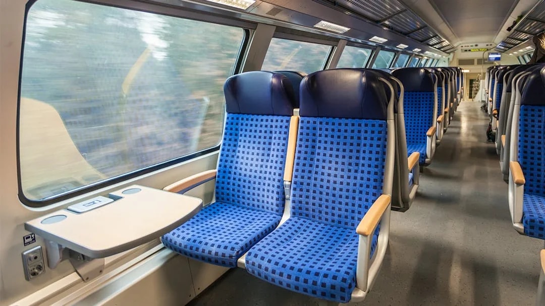 Interior of modern train with blue seats and large windows.