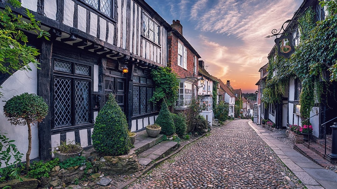 Cobbled street in Windsor lined with historic timber-framed houses at sunset.