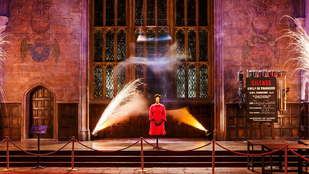 Exhibit at Magical Mischief Tour, Harry Potter London, featuring a pink outfit display in a grand hall.