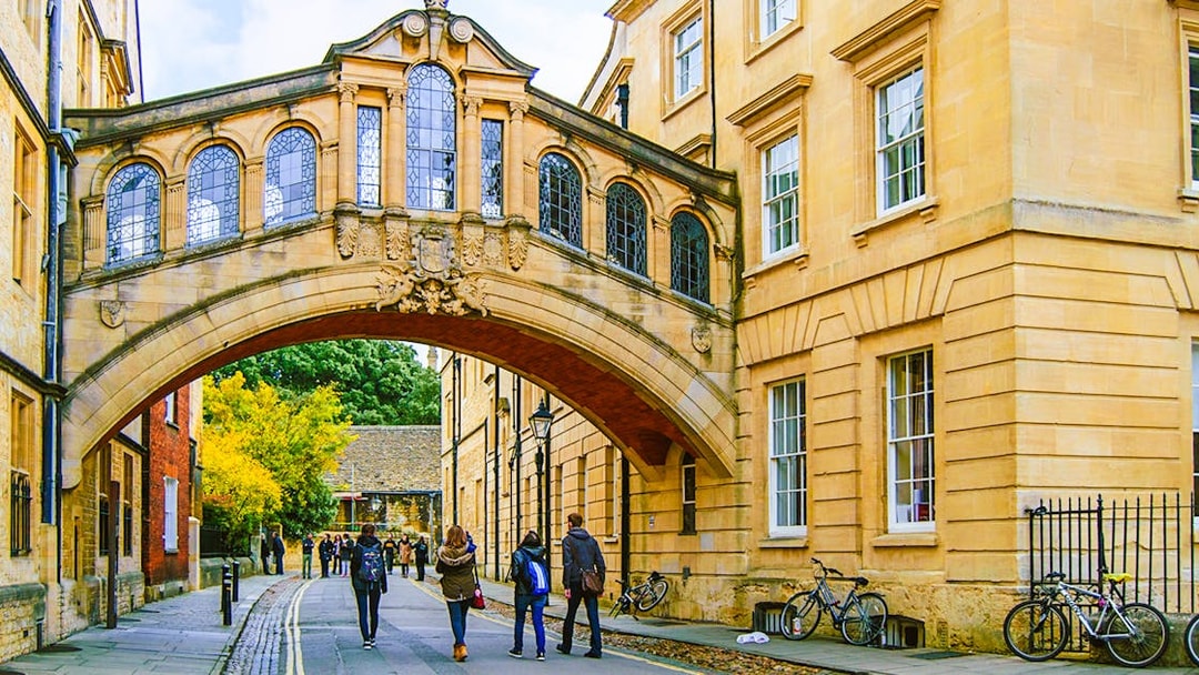 Pedestrians walking under the Bridge of Sighs on the streets of Oxford.