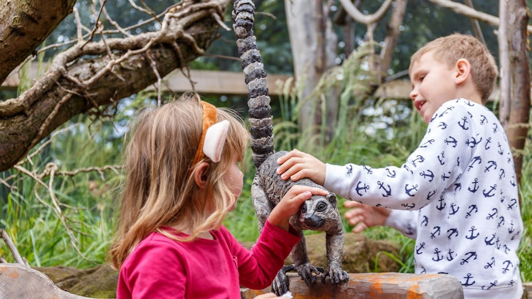 Children interacting with a lemur statue at London Zoo in summer.
