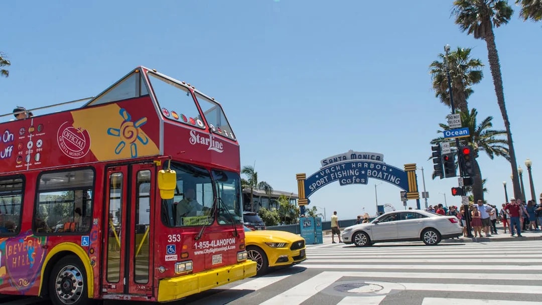 Red double-decker tour bus near Santa Monica Pier entrance, Los Angeles.