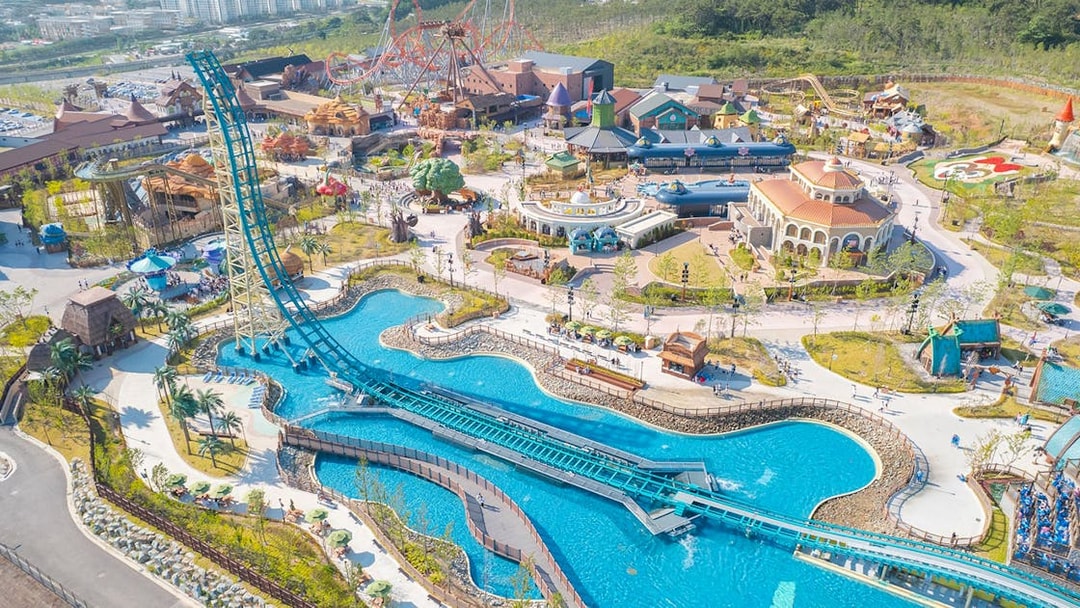 Aerial view of Lotte World Adventure Busan with roller coasters and water attractions.