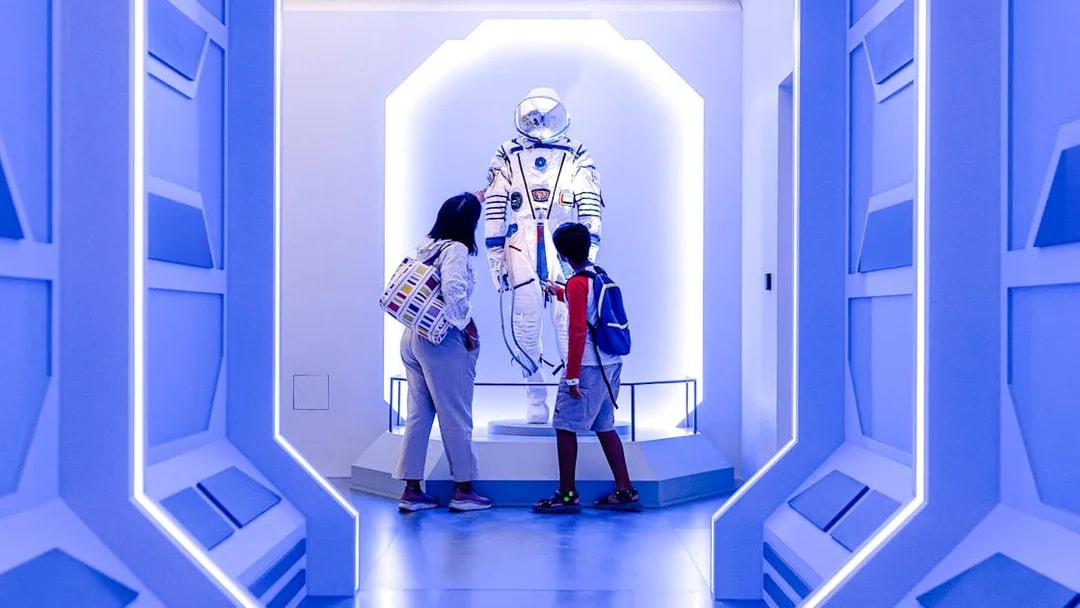 Visitors observing a space exhibit at Louvre Abu Dhabi.