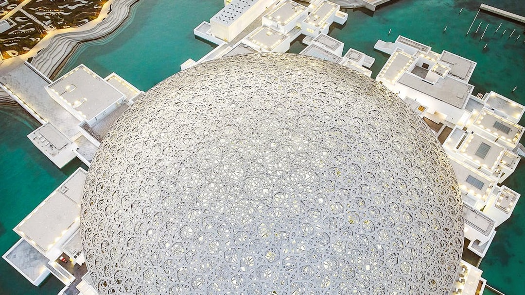 Louvre Museum Abu Dhabi dome with surrounding water and architecture.