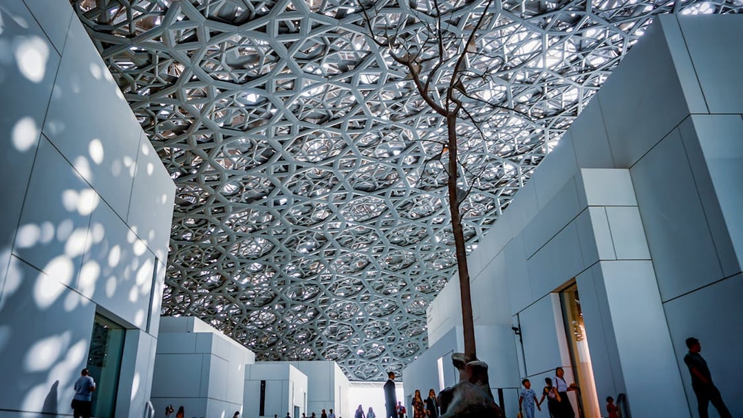 Louvre Abu Dhabi interior with geometric ceiling and visitors exploring.