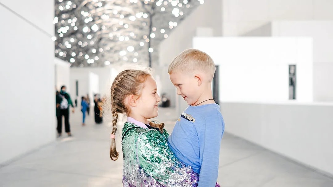 Children smiling under the Louvre Abu Dhabi's dome.