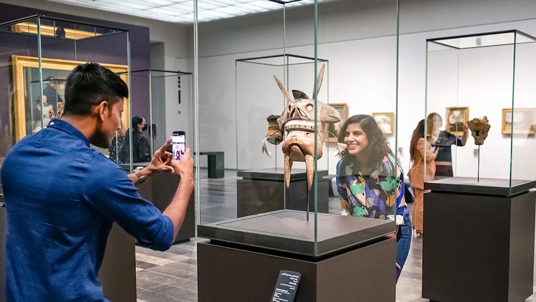 Visitors at Louvre Abu Dhabi viewing an artifact, part of a combo offer with National Aquarium tickets.