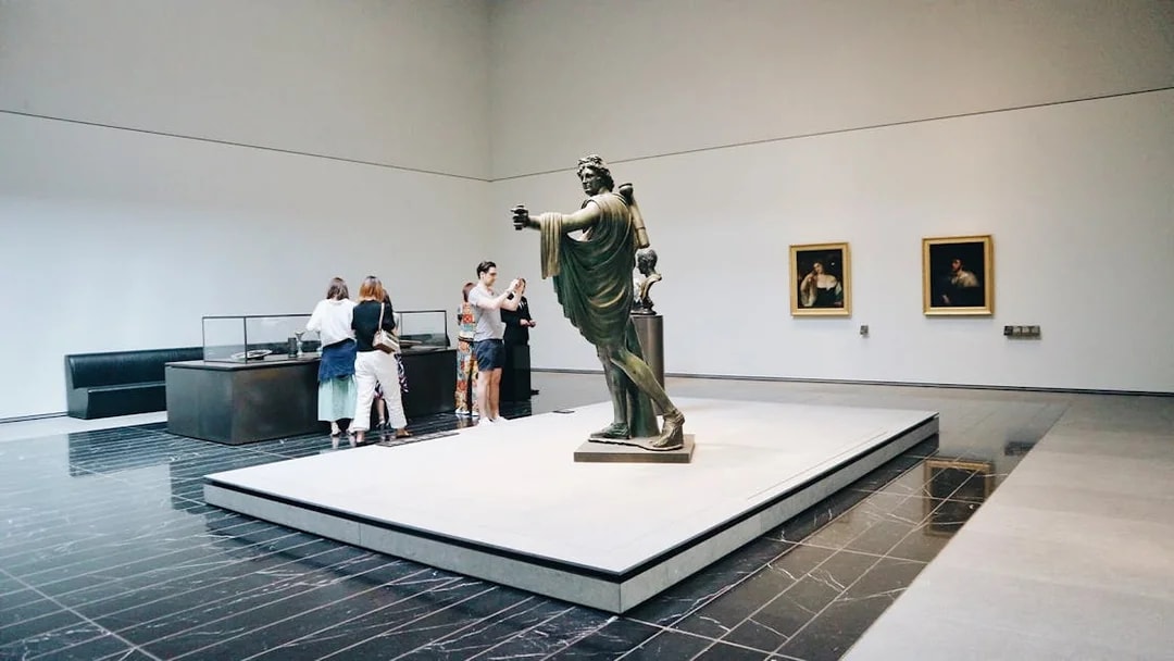 Visitors viewing sculptures and paintings at Louvre Abu Dhabi.