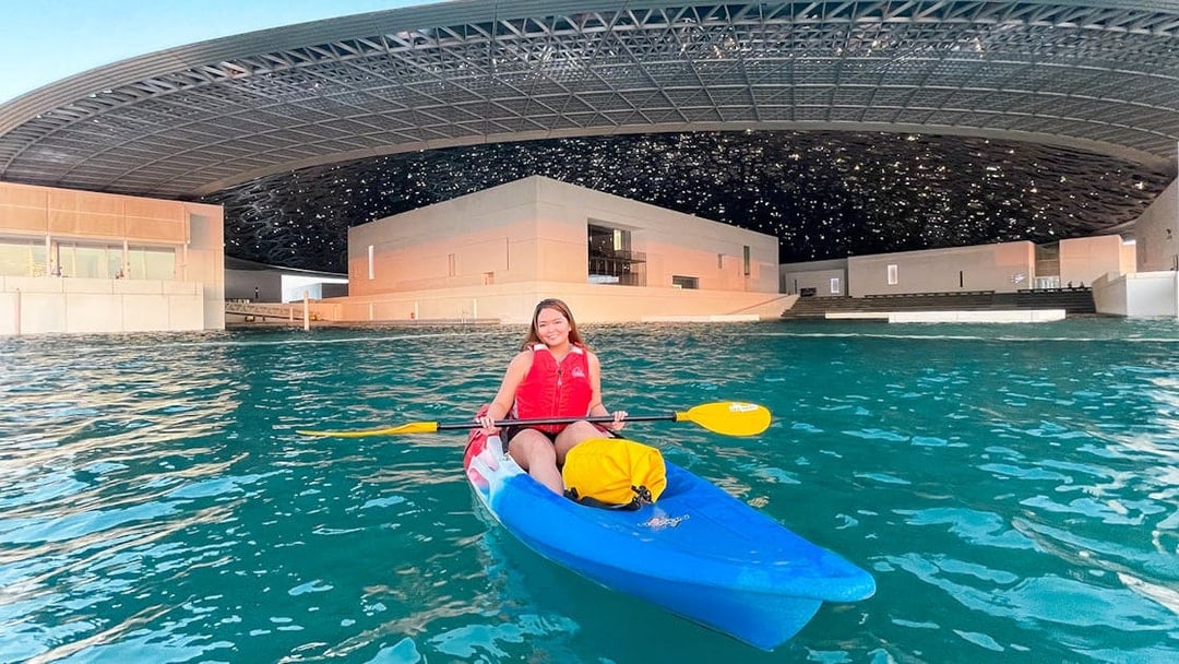Kayaker paddling near Louvre Abu Dhabi's unique architecture.