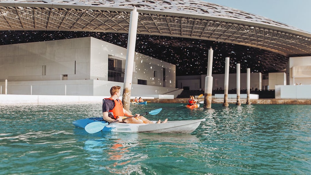 Kayakers paddling near Louvre Abu Dhabi's dome on a guided tour.