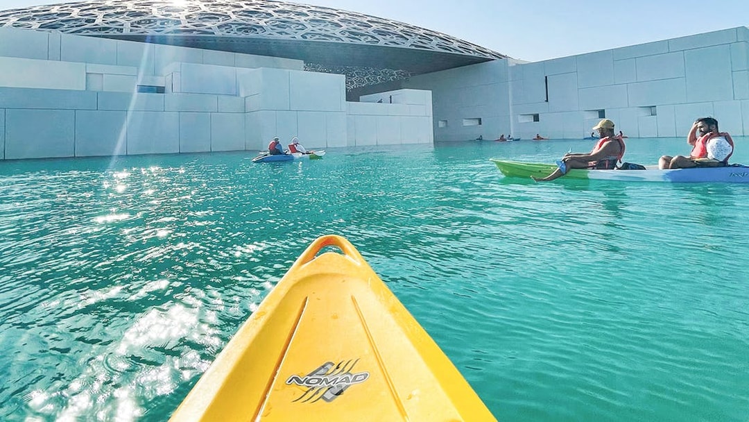 Kayakers paddling near Louvre Abu Dhabi's dome on a guided tour.