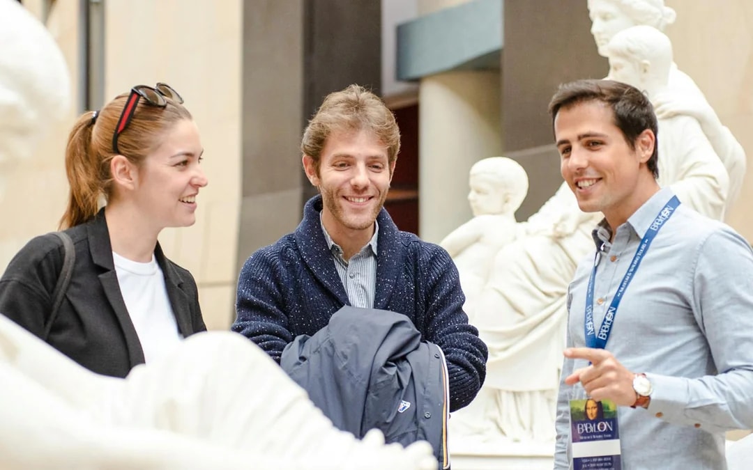 Guide with tourists inside Orsay Museum, France, discussing sculptures.