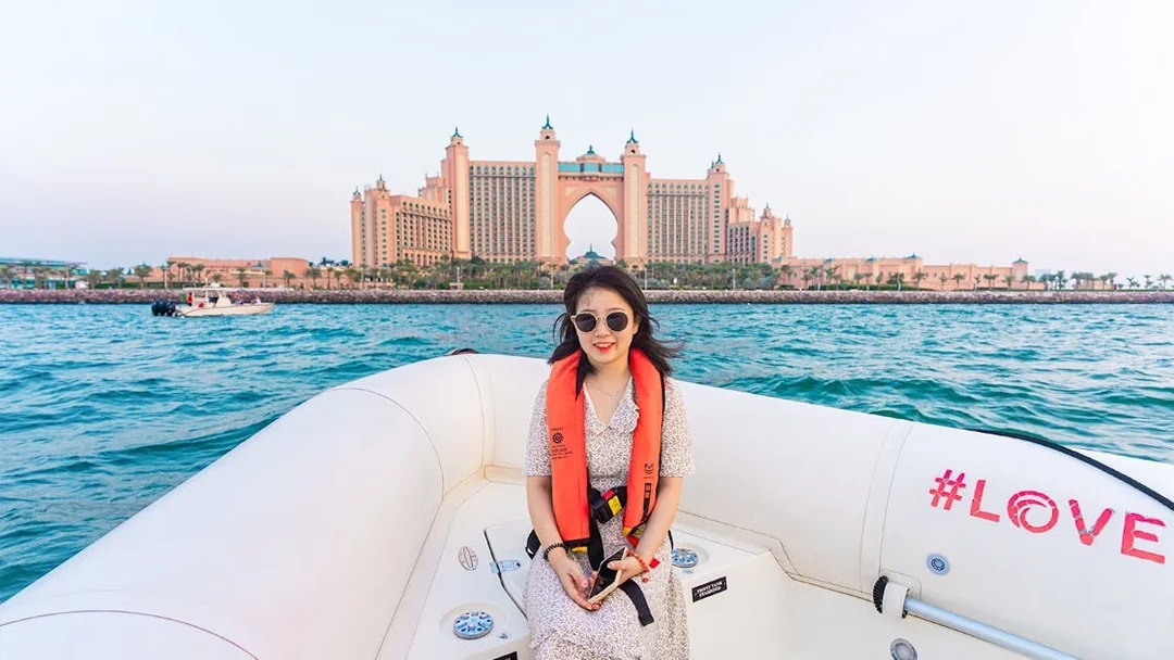 Tourist on a boat with Atlantis The Palm in the background, Dubai Marina tour.