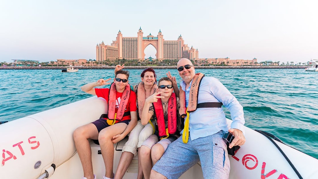 Tourists on a boat tour in Dubai with Atlantis The Palm in the background.