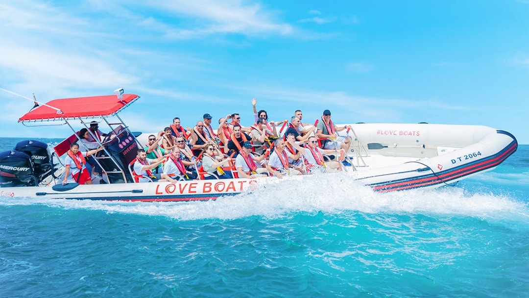 Group enjoying a Love Boats marina tour on a speedboat in clear blue waters.