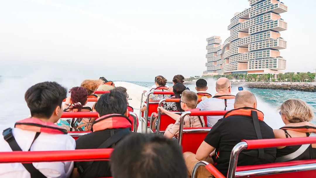 Tourists on a speedboat near unique waterfront buildings during Love Boats Marina Tour.