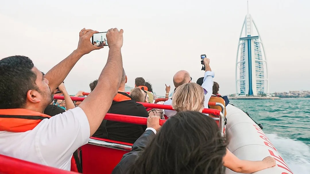 Tourists on a boat capturing the Burj Al Arab in Dubai during a marina tour.
