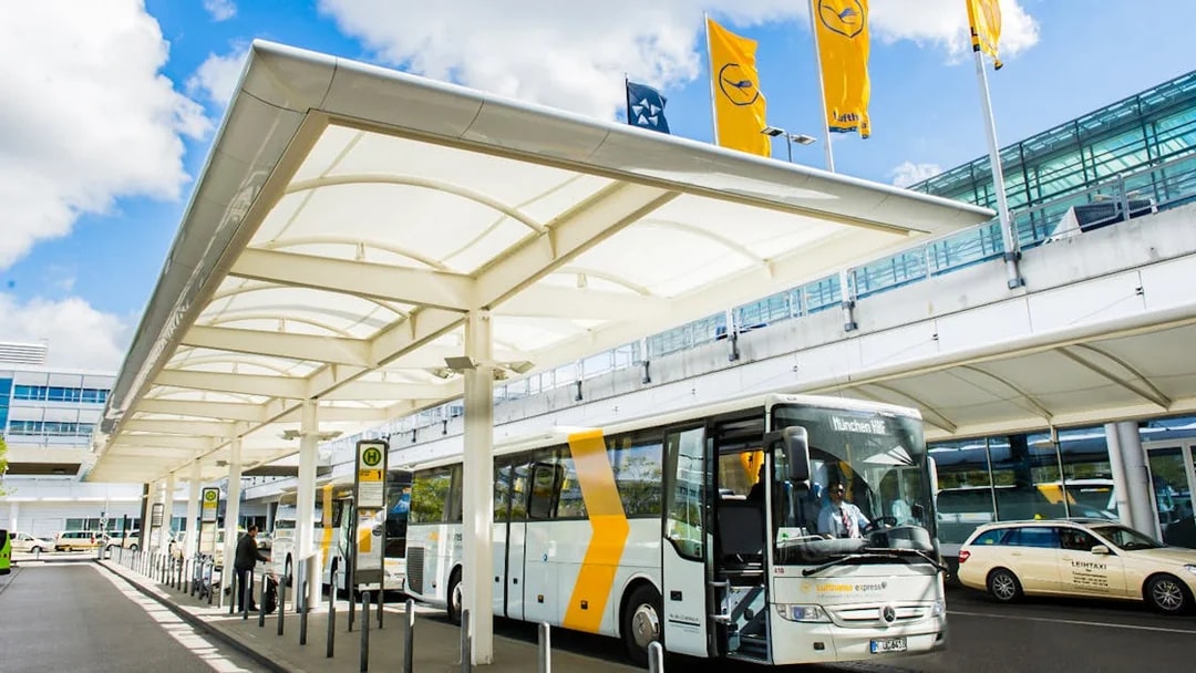 Lufthansa Express Bus at Munich Airport bus station with passengers boarding.