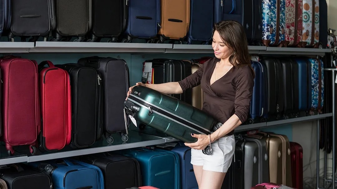 Person examining a suitcase in a luggage store.