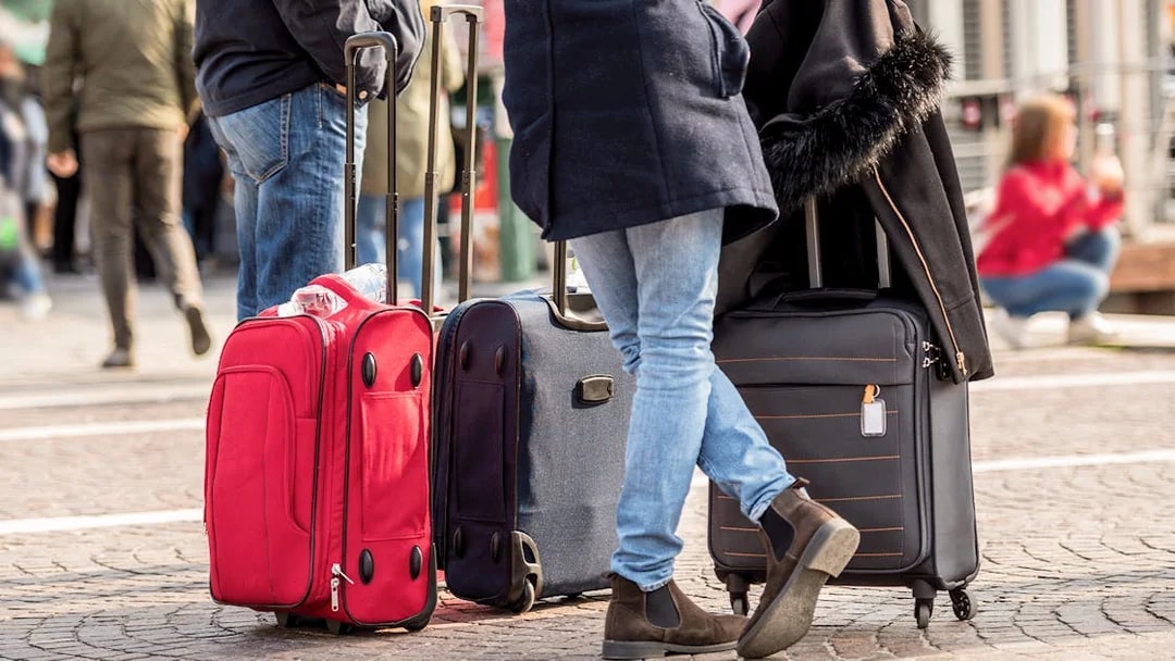Tourists standing with luggage on a city street.