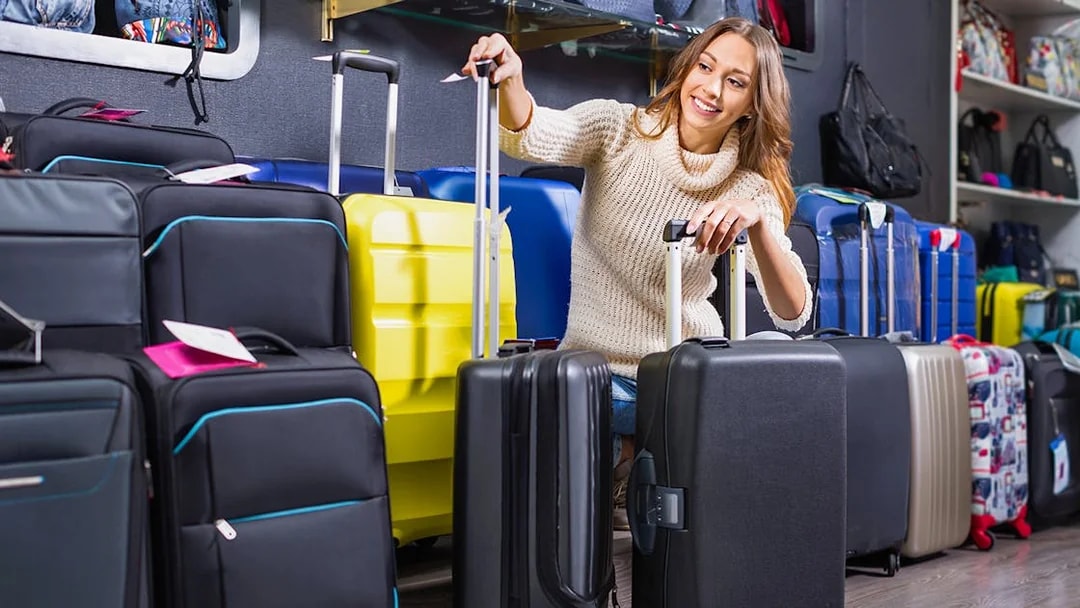 Person selecting suitcases in a luggage store.