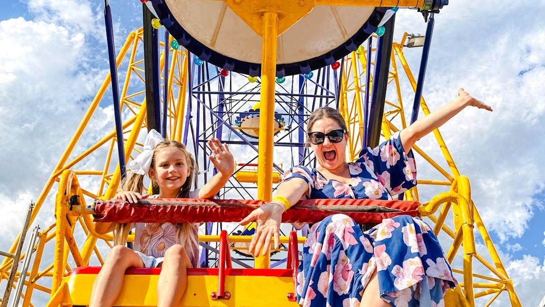 Mother and child on a Ferris wheel at Luna Park, smiling and waving.