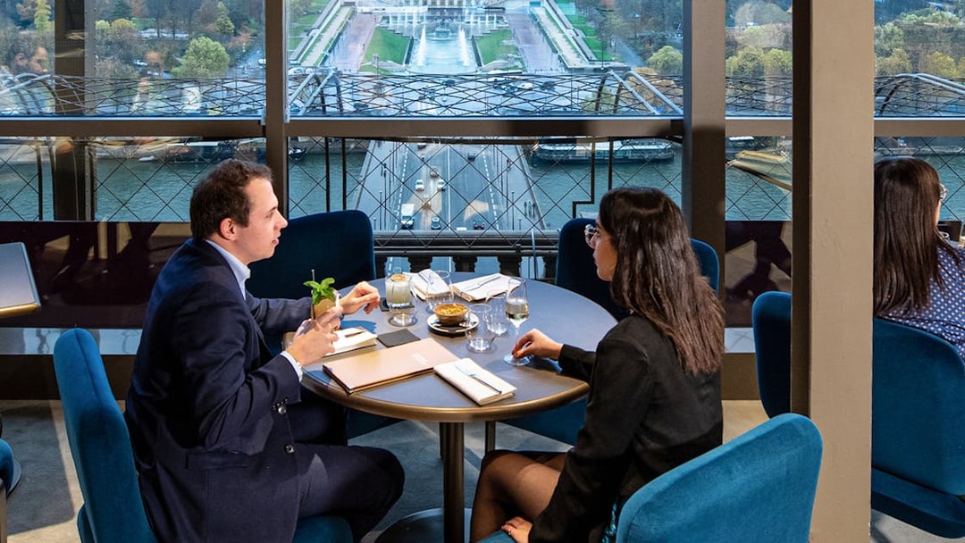 Couple dining at Madame Brasserie with view of Paris skyline.