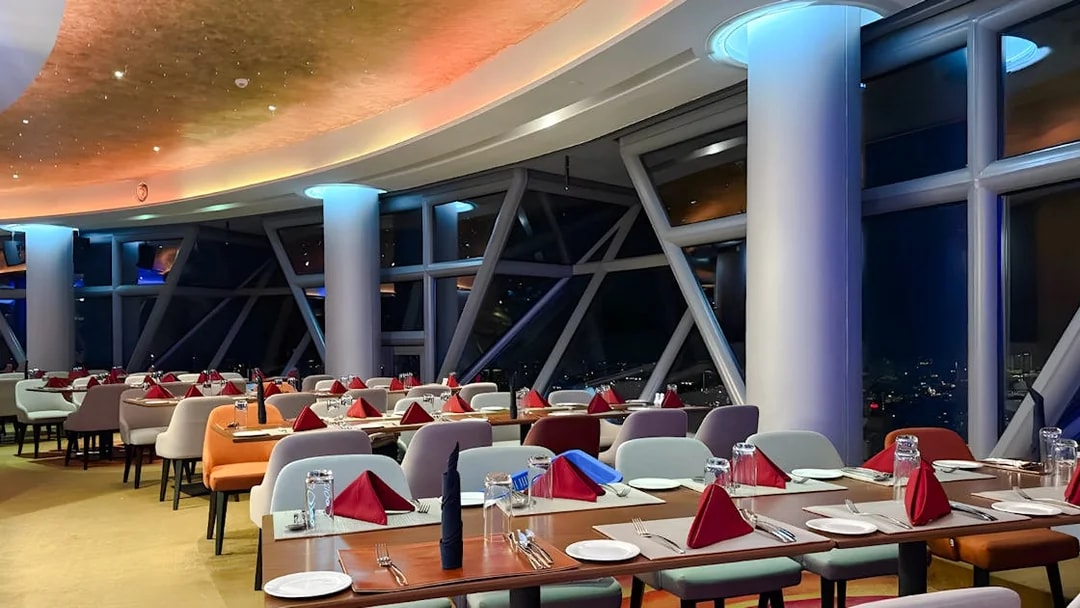 Dining area at Orbit Revolving Restaurant, KL Tower, Kuala Lumpur, with city skyline view.