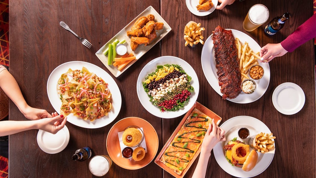Hard Rock Cafe Milan table with nachos, salad, ribs, wings, and burger.