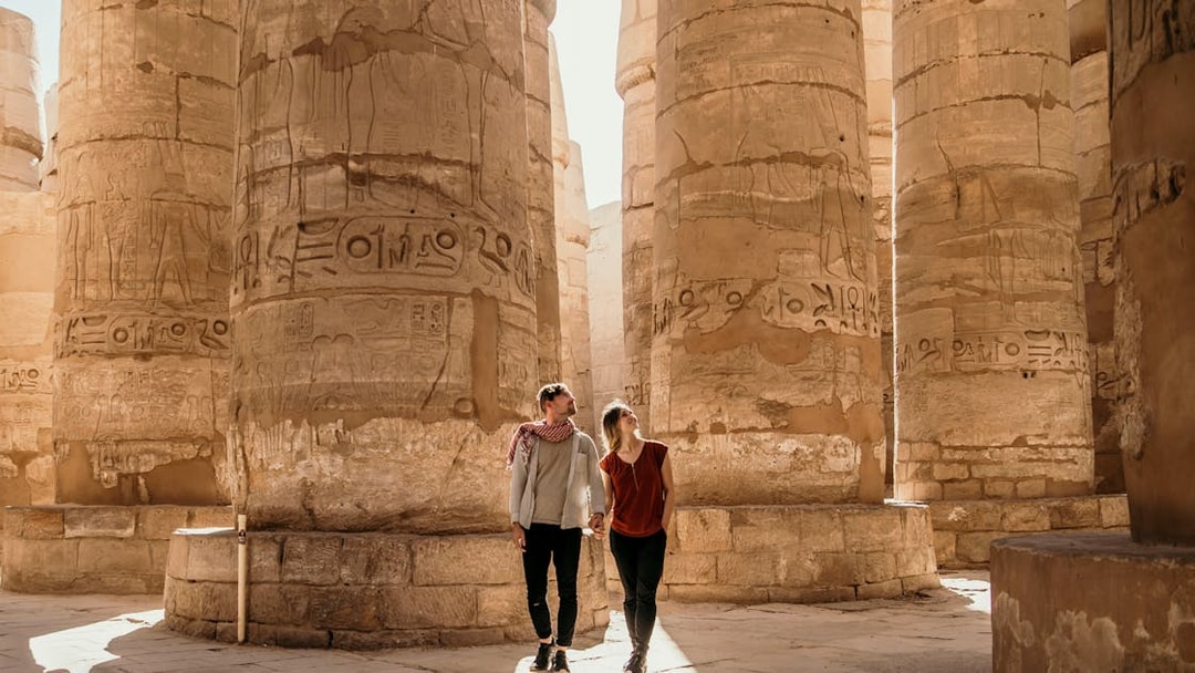 Couple exploring ancient columns at Luxor Temple, Egypt.